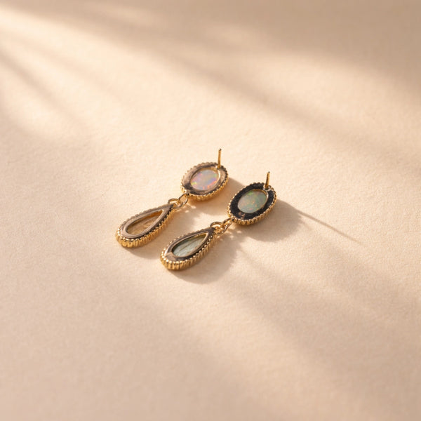 A back view of Ruinette one-of-a-kind-earrings featuring white and black opal, green and peach tourmaline, set in 18k yellow gold