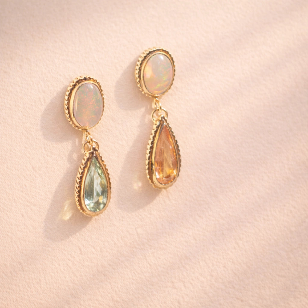 A side angle view of Ruinette one-of-a-kind-earrings featuring white and black opal, green and peach tourmaline, set in 18k yellow gold