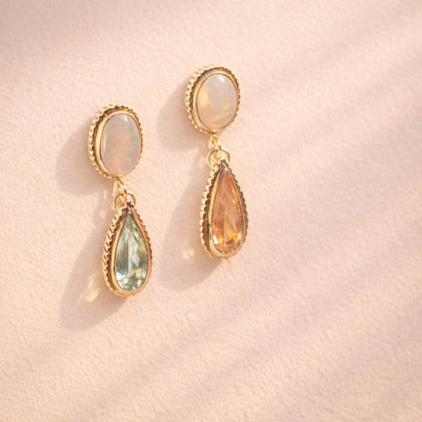 A side angle view of Ruinette one-of-a-kind-earrings featuring white and black opal, green and peach tourmaline, set in 18k yellow gold