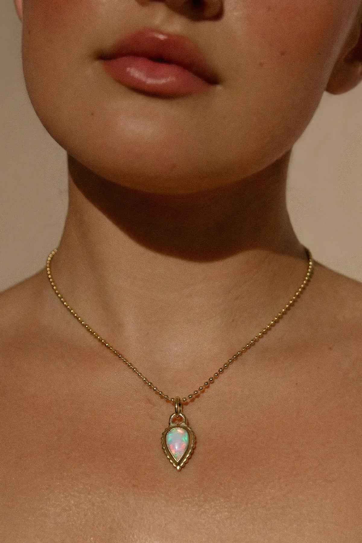 Ruinette Baby Rib Opal Pear Charm in 18k yellow gold, featuring an Australian opal pear cabochon, worn view.