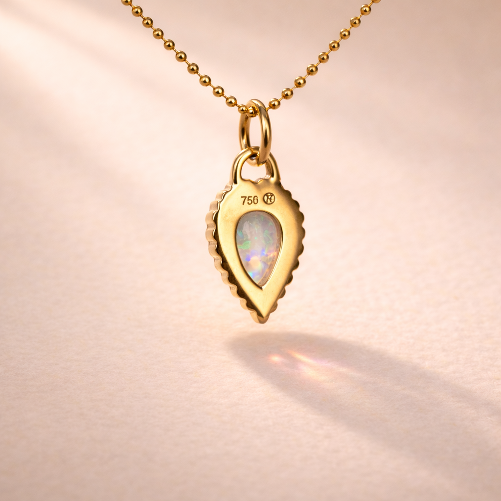 The Cry Baby Rib Charm viewed from the back, showcases 18k yellow gold and a delicate Australian opal pear cabochon, highlighting Ruinette's artisan craftsmanship.