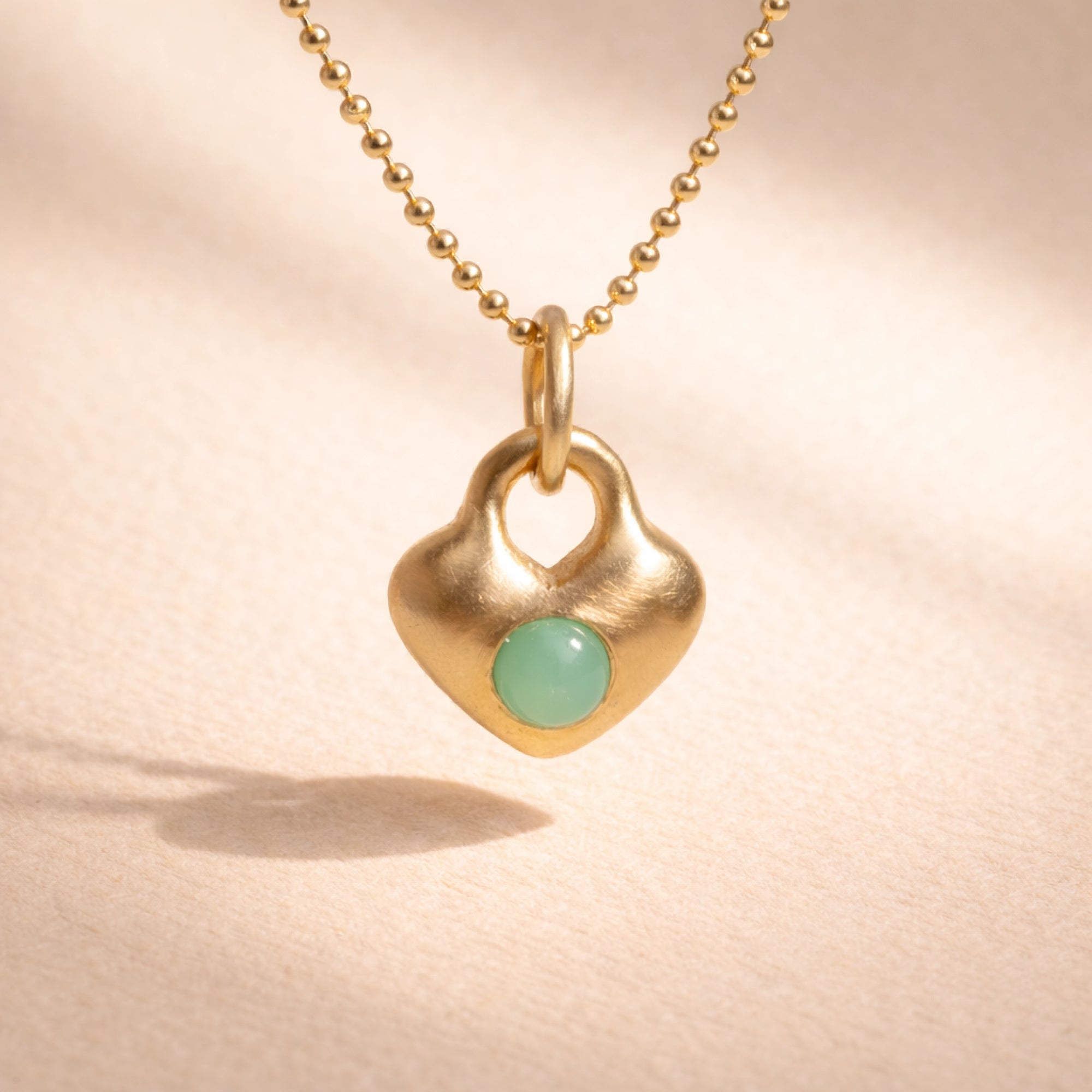 Ruinette Heart Charm in 18k yellow gold with brushed satin finish featuring round bezel-set green chrysoprase cabochon on ball chain, front view